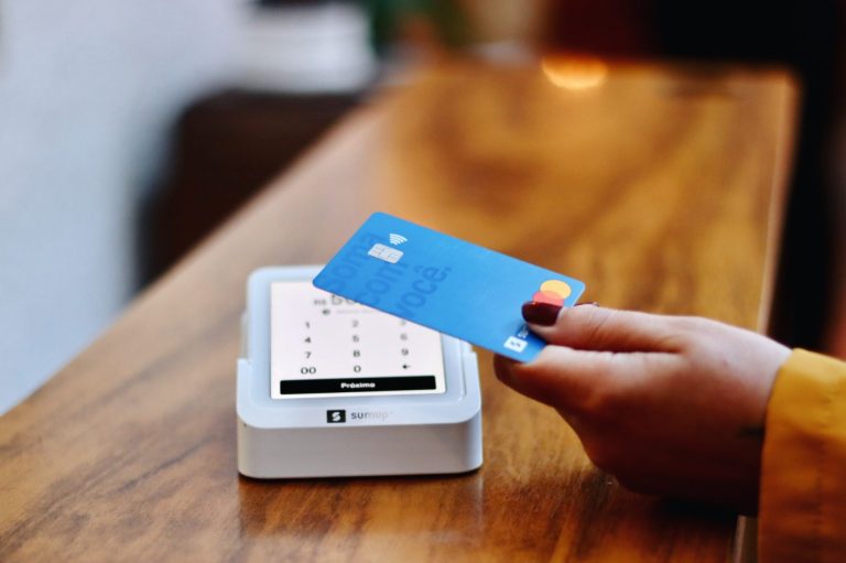Frau hält Kreditkarte an ein Kartenlesegerät